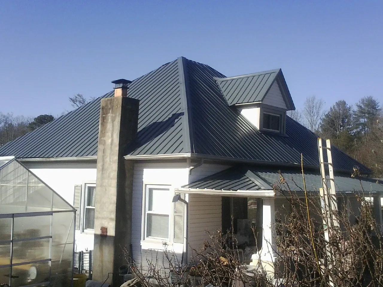 Dark blue standing seam metal roof on a white farmhouse with dormer — Slate & Tile Roof Repair by Roofing Brothers in East Orange
