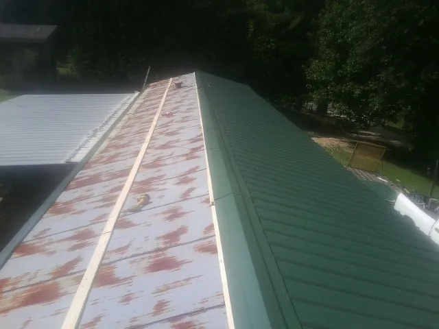 Old rusted panels beside newly installed green metal roofing — Wind Damage Roof Repair by Roofing Brothers in East Orange