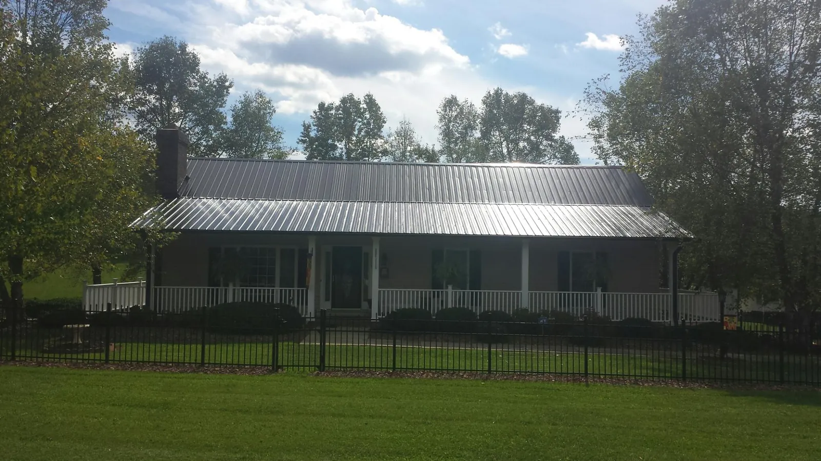 Gray metal roof on a brick ranch with a full width front porch — Gutter Guard Installation work by our crew in East Orange