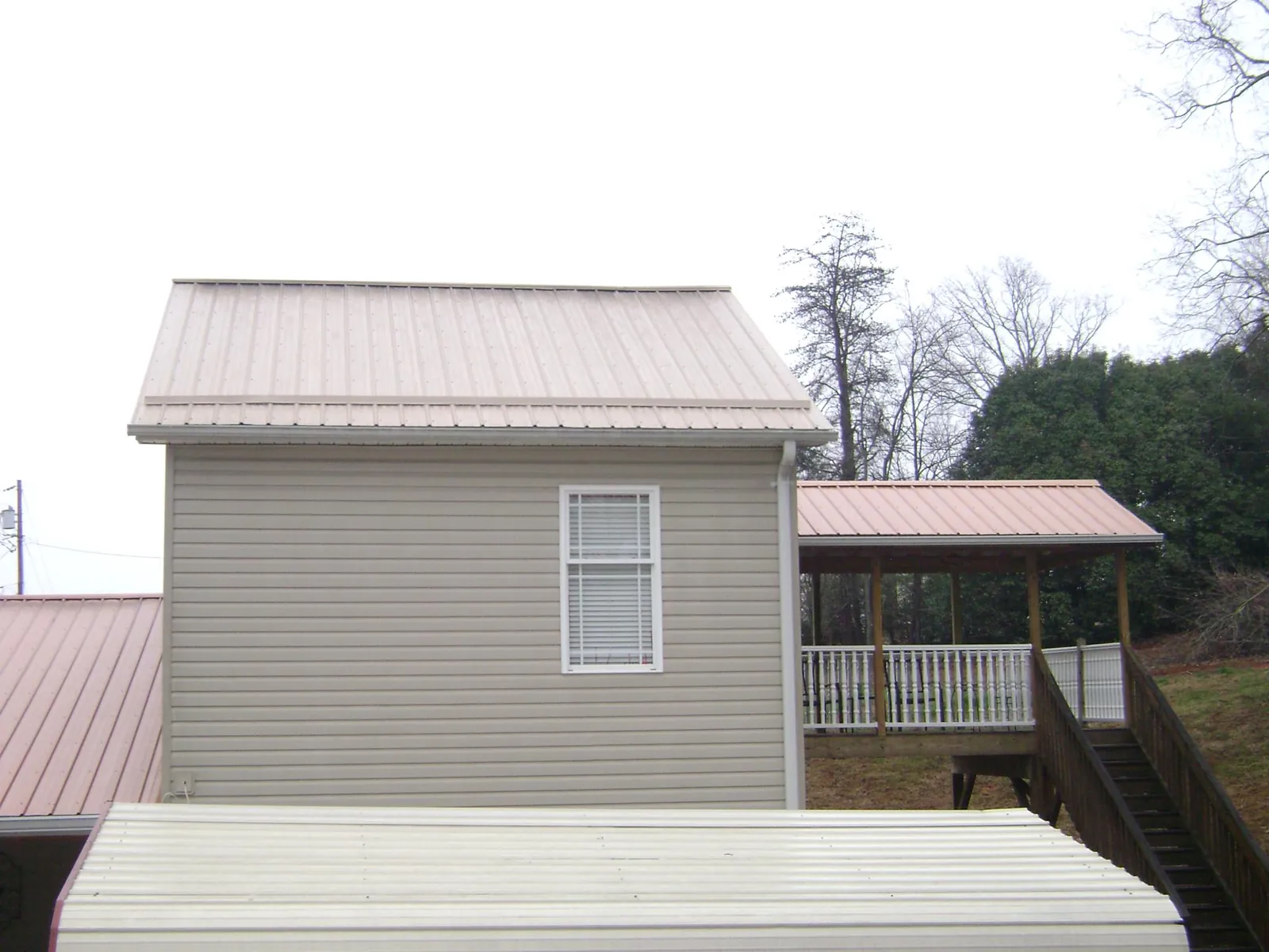 Tan metal roofs on a two story addition and attached porch, from a Roof Replacement job in East Orange