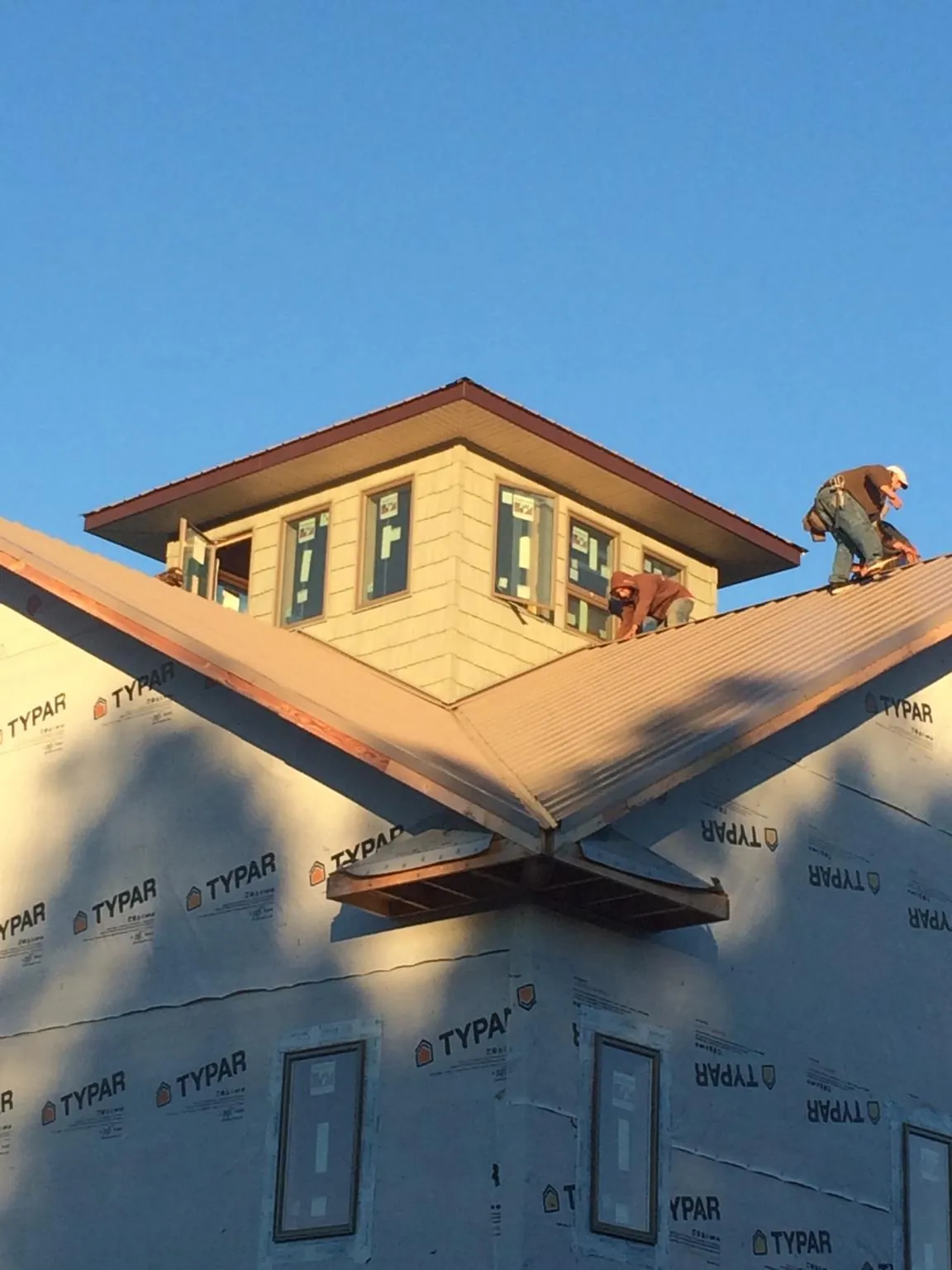 Roofers working around a rooftop cupola on a new metal roof at sunset — Roof Waterproofing in East Orange by Roofing Brothers